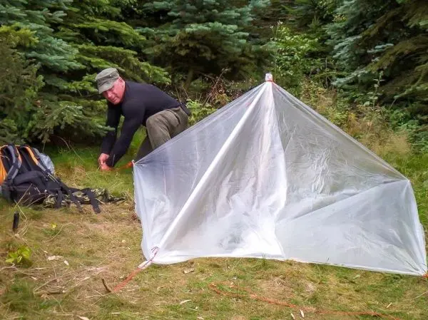 Mann spannt eine Tarp-Notunterkunft mit Abspannschnur auf