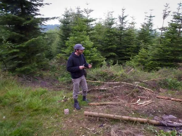 Mann steht in einem Waldgebiet und hält ein Messer in der Hand