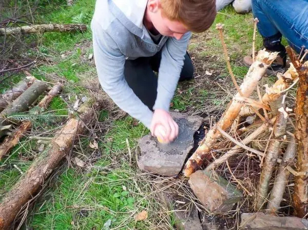 Person schlägt einen Stein auf einen anderen Stein