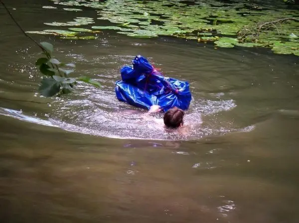 Person schwimmt mit blauer Tarp-Notunterkunft im Wasser
