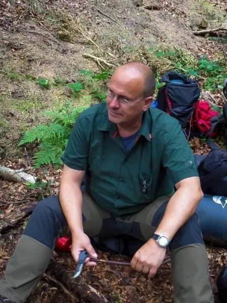Person sitzt auf dem Boden und hält einen Stock in der Hand