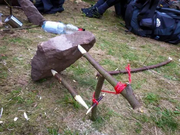 Schlagfalle (Figure-Four) mit Stein und Holzstöcken auf dem Boden
