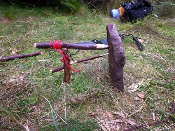 Selbstgebaute Konstruktion aus Ästen und einem Stein im Gras
