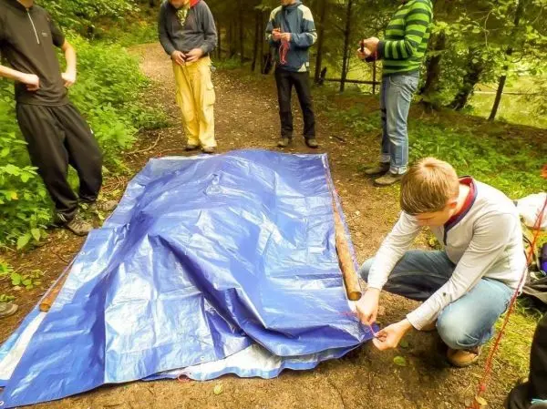 Tarp-Notunterkunft wird von mehreren Personen auf dem Boden vorbereitet