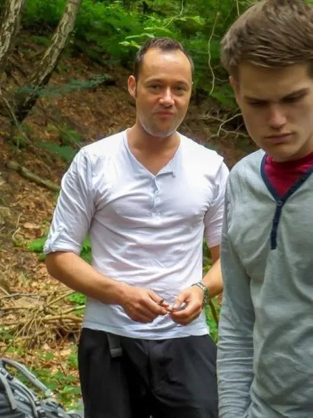 Zwei Personen stehen im Wald, eine hält etwas in der Hand
