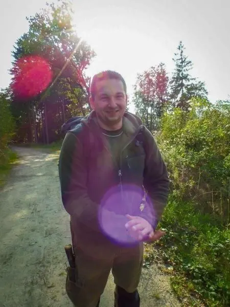 Ein Mann steht auf einem Waldweg und hält die Hände zusammen