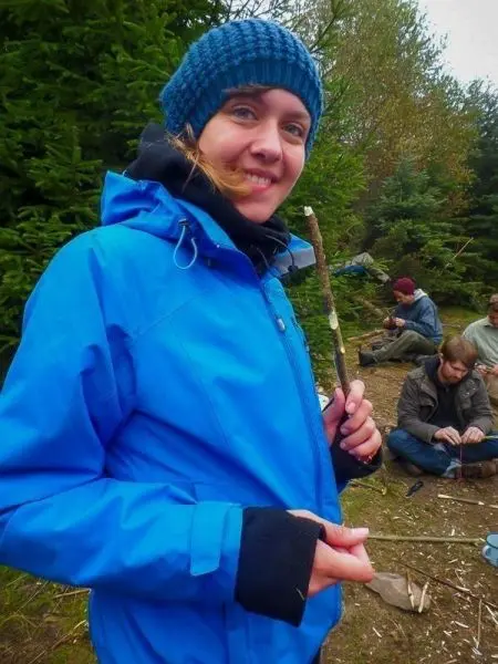 Frau hält einen Stock in der Hand, während im Hintergrund andere Personen arbeiten