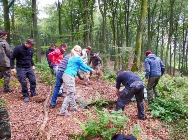 Gruppe arbeitet gemeinsam im Wald mit Werkzeugen und Materialien beim Überlebenstraining