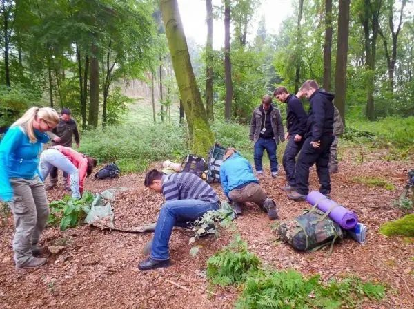 Gruppe von Personen übt im Wald mit Rucksäcken und Ausrüstung