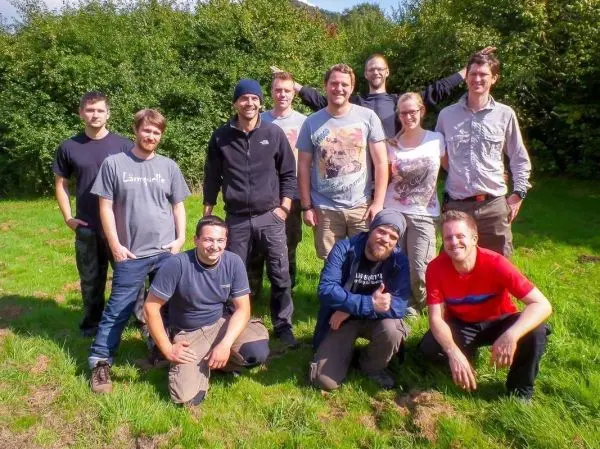 Gruppierung von zehn Personen im Freien auf einer Wiese, umgeben von Bäumen