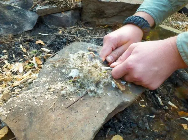 Hände bearbeiten Zunder auf einem Stein, um Funken zu erzeugen