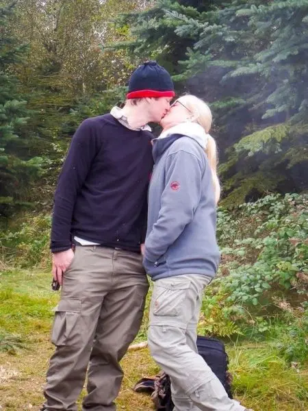 Küssen sich in der Natur, umgeben von Bäumen und Sträuchern