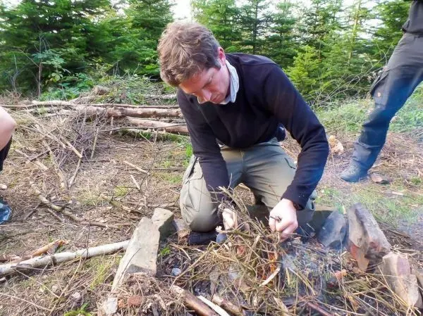 Mann bereitet Zunder in einer Feuerstelle aus Steinen vor
