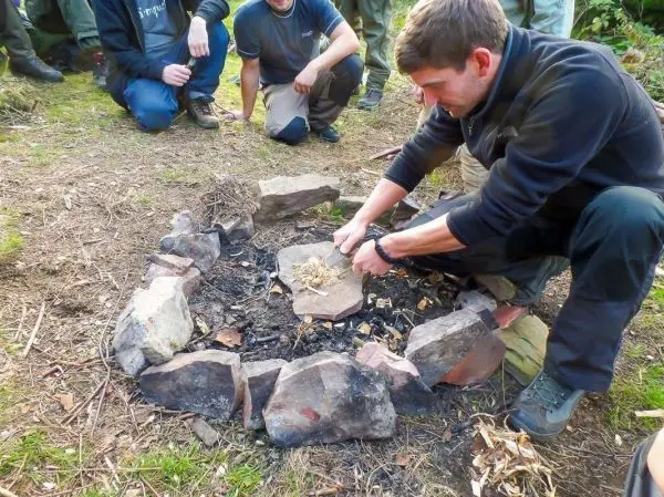 Person bereitet Feuerstelle mit Zunder vor beim Survival Training