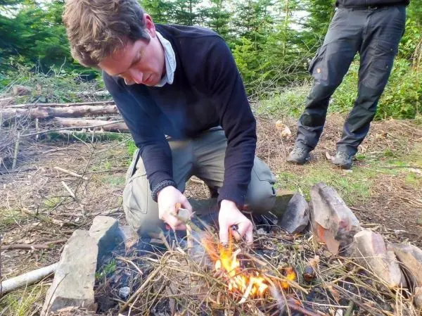 Zunder glimmt in einem kleinen Bodenfeuer zwischen Steinen