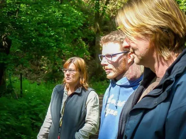 Drei Personen stehen im Wald und schauen nach vorne
