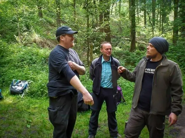 Drei Personen stehen im Wald und unterhalten sich aktiv