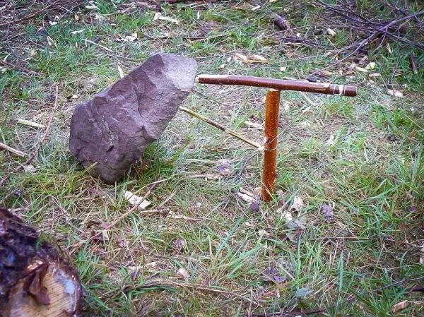 Ein Stein liegt auf einem Holzgestell im Gras