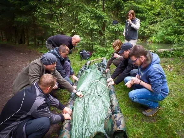 Gruppe arbeitet gemeinsam an einer Tarp-Notunterkunft im Wald