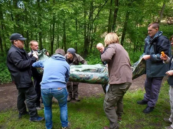 Gruppierung hebt eine improvisierte Trage mit einer Person darin an