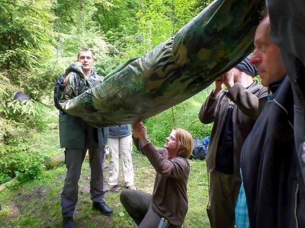 Gruppierung von Personen beim Aufbau einer Tarp-Notunterkunft im Wald