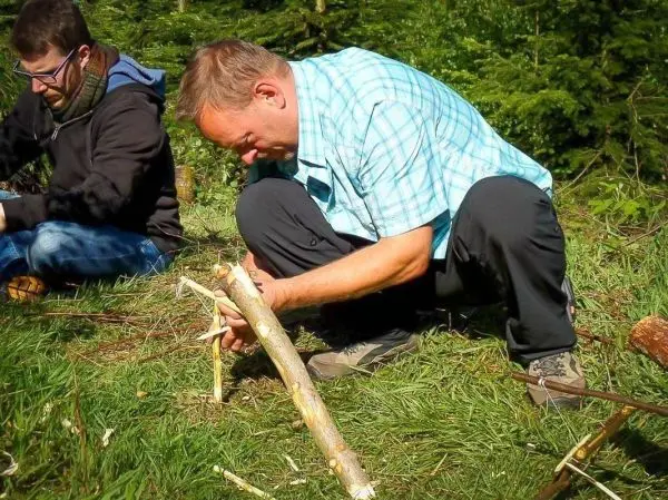 Mann bearbeitet einen Holzstock mit einem Messer im Wald
