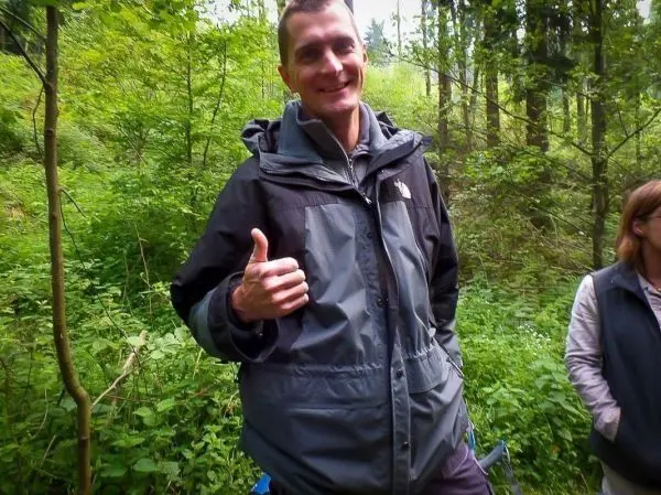 Mann gibt Daumen hoch in bewaldeter Umgebung mit dichter Vegetation