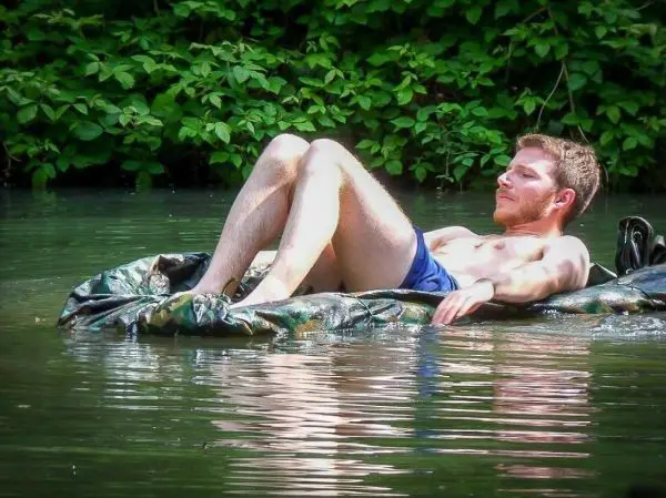 Mann liegt auf einer aufblasbaren Matratze im Wasser zwischen Pflanzen