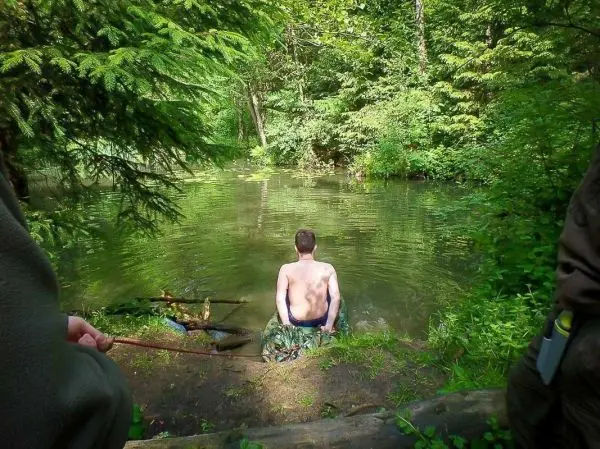 Mann sitzt am Ufer eines Gewässers und blickt ins Wasser