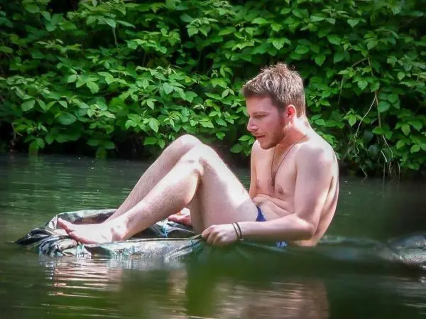 Mann sitzt auf einer improvisierten Schwimmhilfe im Wasser