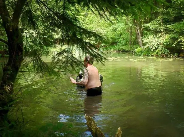 Mann steht im Wasser und hält einen Gegenstand in der Hand