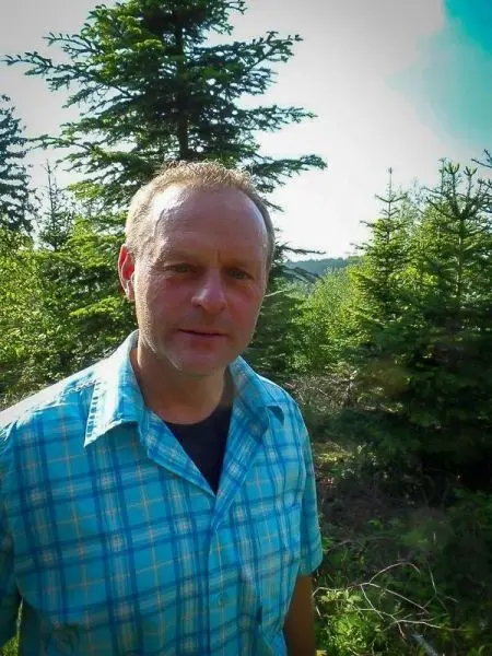 Mann steht zwischen grünen Bäumen im Wald