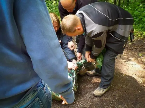 Mehrere Personen sichern eine improvisierte Trage mit einem grünen Tuch