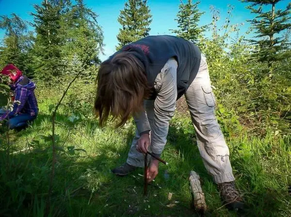 Person bearbeitet Holzstück im Wald