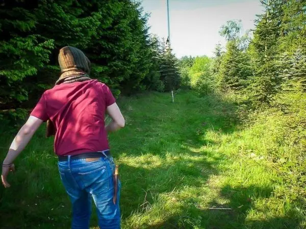 Person geht einen schmalen Weg entlang zwischen Bäumen