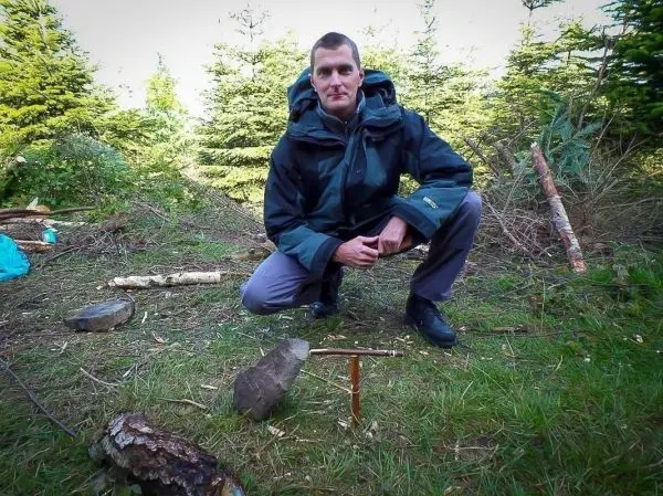 Person kniet neben einem Holzstück und einem Werkzeug