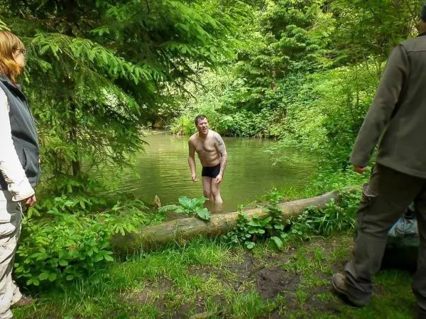 Person steht im Wasser und lächelt, zwei Personen beobachten ihn
