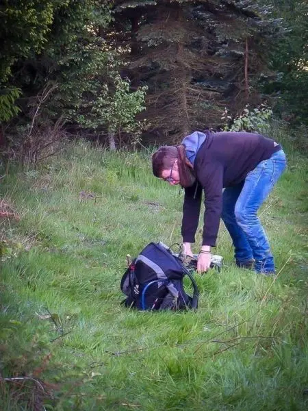 Rucksack steht auf dem Boden, Person beugt sich nach vorne und greift hinein