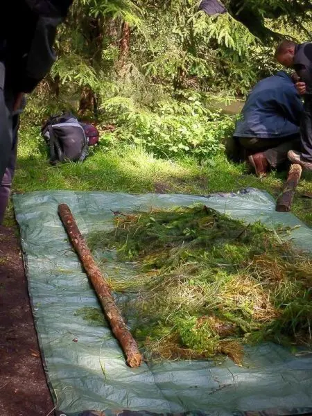 Tarp-Notunterkunft mit Gras und Ästen auf dem Boden vorbereitet