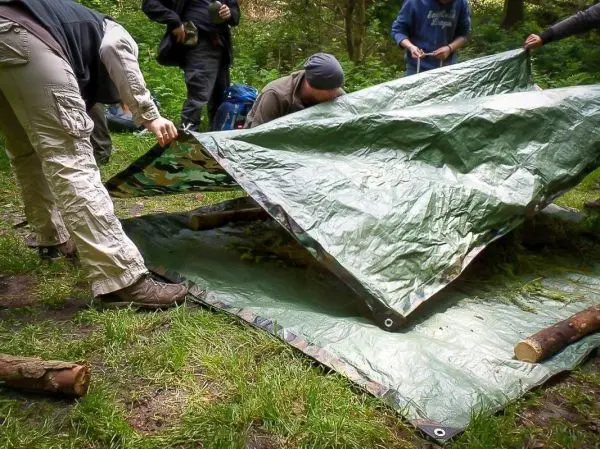 Tarp-Notunterkunft wird von mehreren Personen aufgebaut