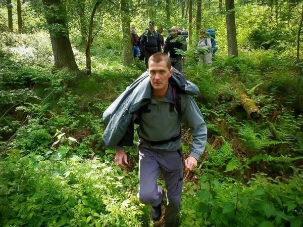 Wanderer mit Rucksack überquert unebenes Gelände im Wald