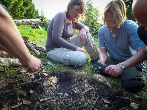 Zunder wird vorbereitet, während zwei Personen auf dem Boden sitzen und beobachten