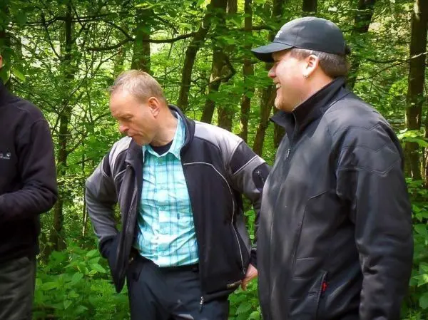 Zwei Männer stehen in einem Wald und unterhalten sich