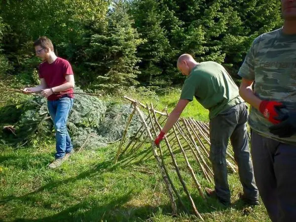 Zwei Personen bauen eine Struktur aus Ästen im Freien