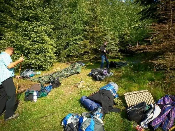 Zwei Personen sortieren Rucksäcke und Ausrüstung im Wald