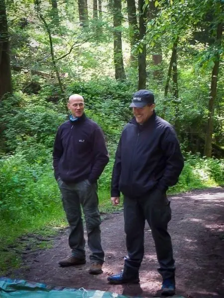 Zwei Personen stehen auf einem Waldweg und unterhalten sich