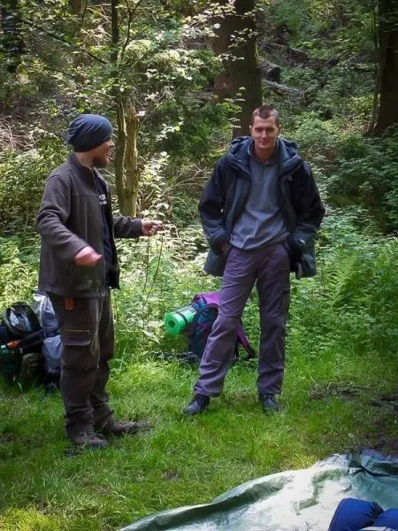 Zwei Personen stehen in einem Waldgebiet neben Rucksäcken und Ausrüstung