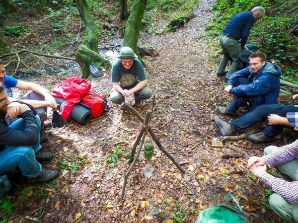 Dreibein aus Ästen steht auf dem Boden, um einen Kessel zu halten