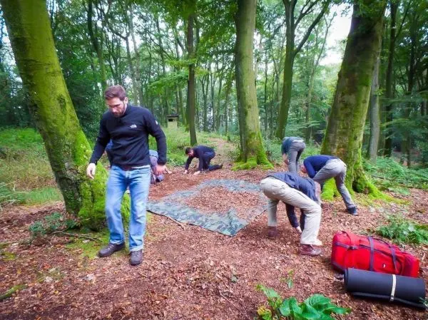 Gruppierung von Personen bereitet Tarp-Notunterkunft im Wald vor