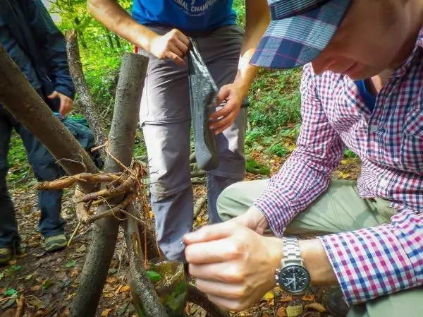 Mann bindet Äste mit Wurzelmaterial zu einer stabilen Konstruktion